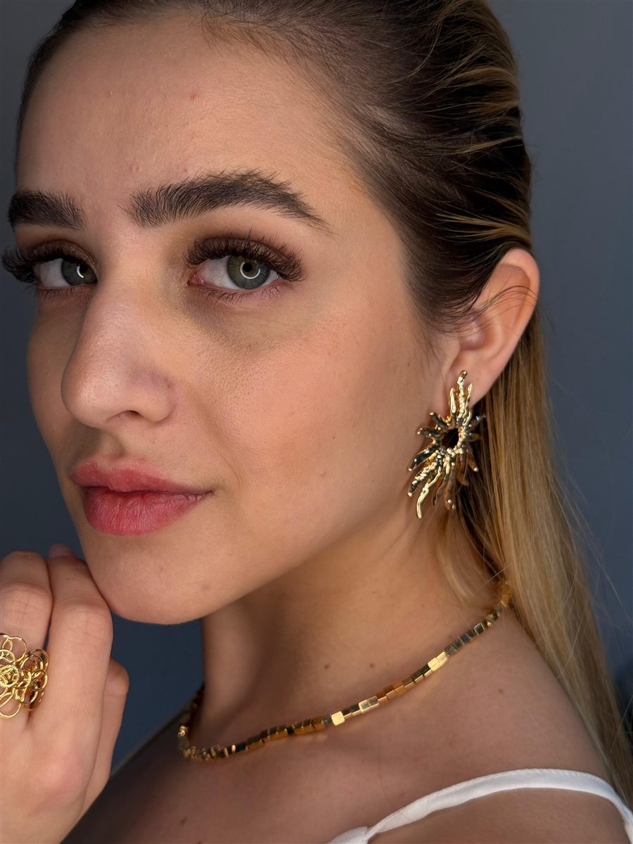 Cliente usando brinco dourado, choker e anel